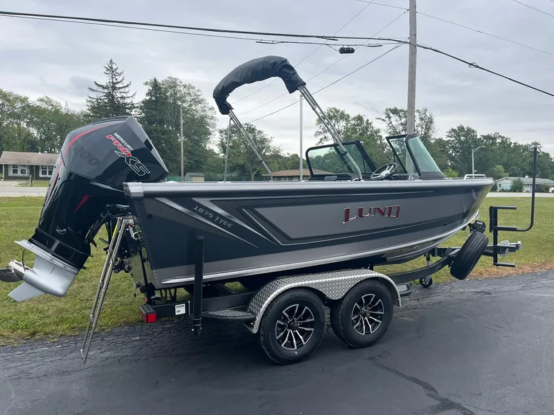 Slide: The Image of 2025 Lund 1875 Tyee boat on trailer, parked outdoors, with Mercury engine. - 3