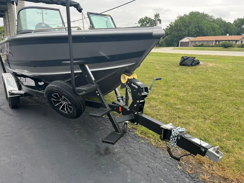Slide: The Image of 2025 Lund 1875 Tyee boat on trailer, parked on driveway near grassy area. - 4