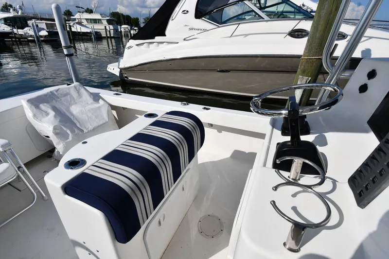Slide: The Image of 2021 Eastern 248 Center Console boat interior with striped seating and docked yachts. - 12