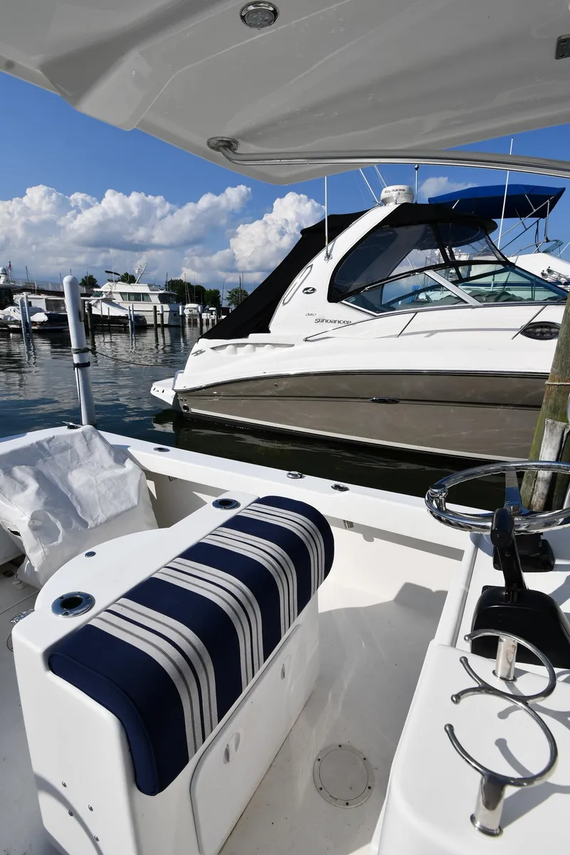 Slide: The Image of 2021 Eastern 248 Center Console boat docked at a marina with a striped seat. - 13
