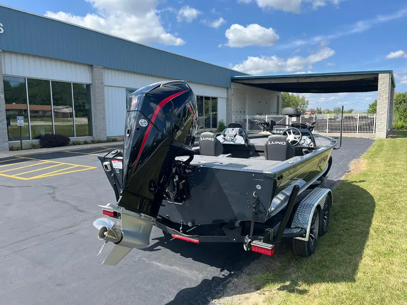 Slide: The Image of 2025 Lund 2075 Pro-V Bass XS boat parked outside a building under a clear sky. - 3