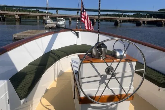 Slide: The Image of Custom 1996 Bolger PH Shoal-draft Ketch with helm, American flag, and waterfront view. - 13