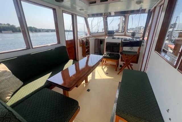 Slide: The Image of Interior of 1996 Custom Bolger PH Shoal-draft Ketch with seating and helm, overlooking water. - 14
