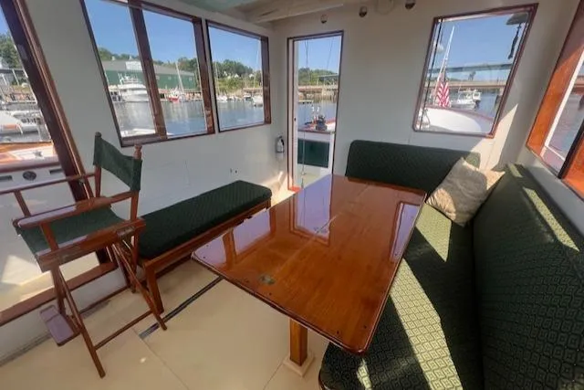 Slide: The Image of Interior of 1996 Custom Bolger PH Shoal-draft Ketch with wooden table and green seating. - 21