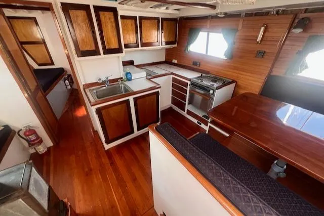 Slide: The Image of Interior of 1996 Custom Bolger PH Shoal-draft Ketch with wooden cabinetry and kitchen area. - 25