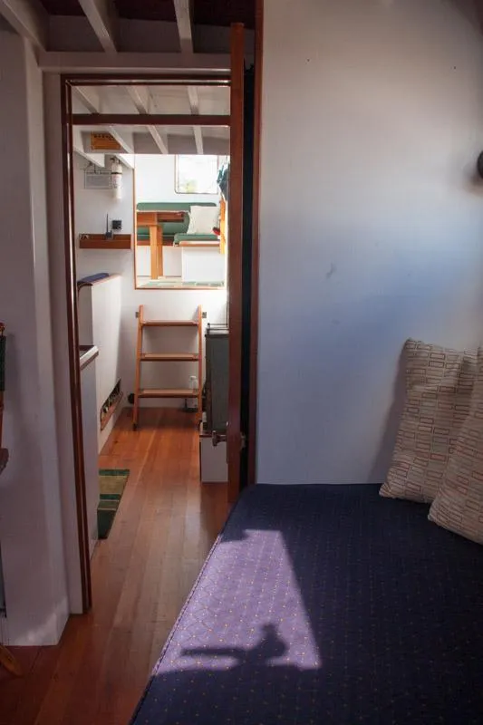 Slide: The Image of Interior of 1996 Custom Bolger PH Shoal-draft Ketch, featuring cozy seating and wooden flooring. - 7