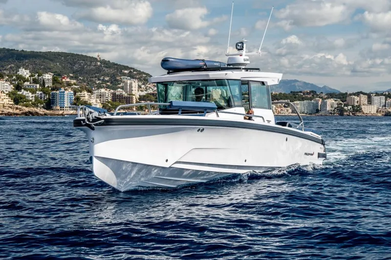 Slide: The Image of 2025 Axopar 29 XC Cross Cabin cruising on blue ocean near coastal city. - 1