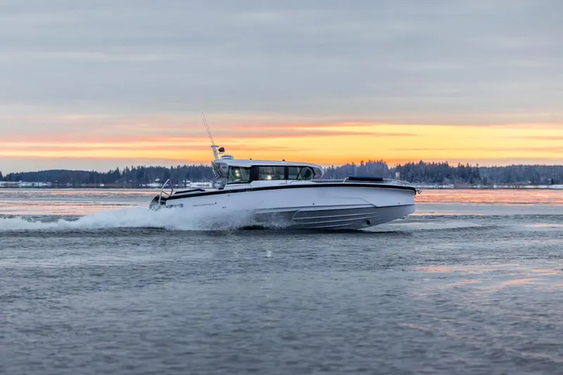Slide: The Image of 2025 Axopar 29 XC Cross Cabin boat cruising at sunset on calm waters. - 3