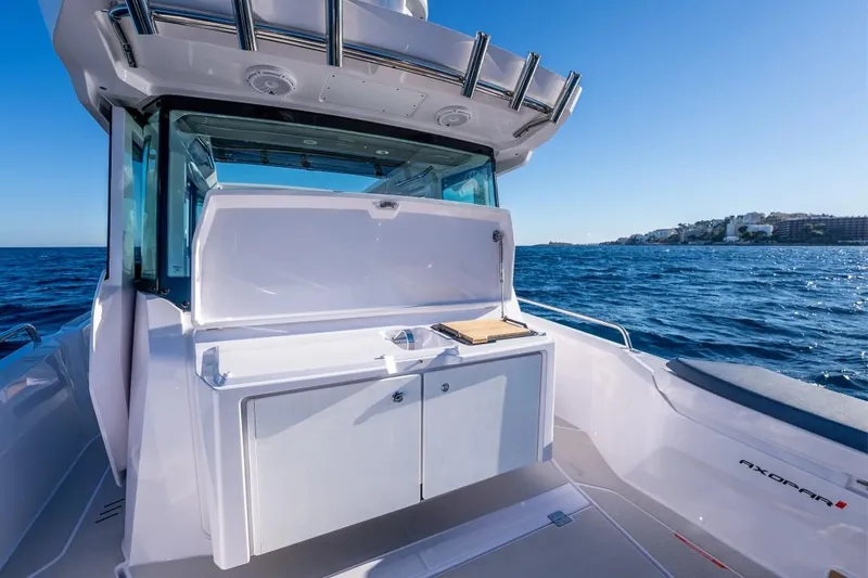 Slide: The Image of 2025 Axopar 29 XC Cross Cabin boat with open deck storage, cruising on blue ocean waters. - 8