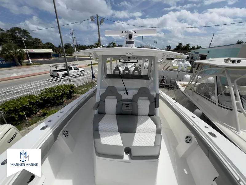 Slide: The Image of 2024 Regulator 37 boat with sleek seating, docked at Mariner Marine under a partly cloudy sky. - 14