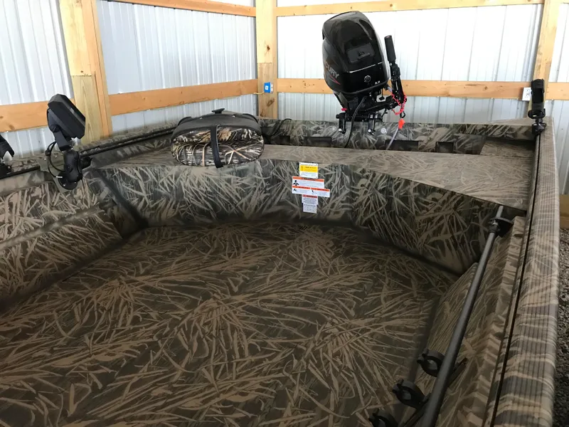 Slide: The Image of 2022 Crestliner 1760 Retriever Jon boat with camouflage interior and outboard motor. - 4