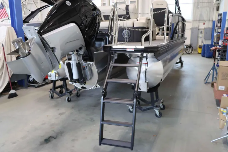 Slide: The Image of 2025 Barletta Lusso 23U pontoon boat in a workshop with ladder and outboard motor. - 4