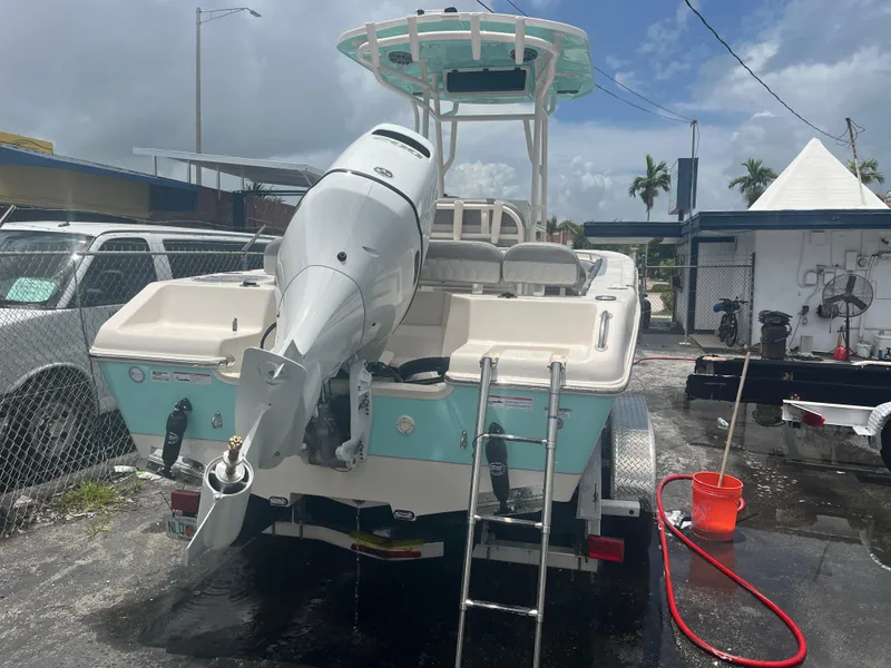 Slide: The Image of 2025 Sea Chaser 22 HFC boat with outboard motor and ladder, parked on a trailer. - 13