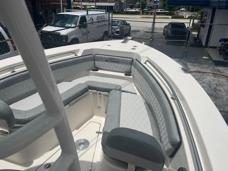 Slide: The Image of 2025 Sea Chaser 22 HFC boat with cushioned seating in a marina. - 18