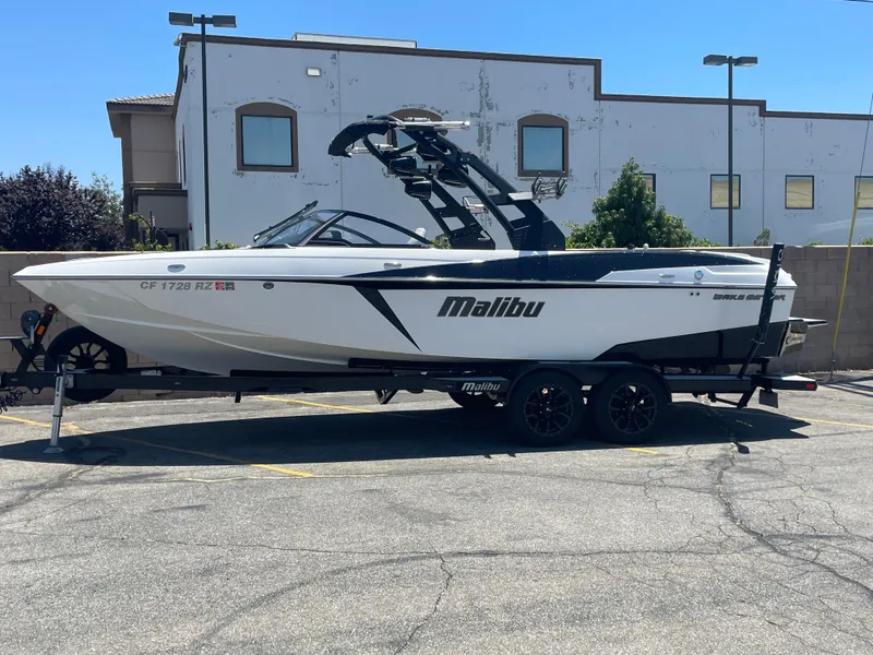 Slide: The Image of 2017 Malibu Wakesetter 25 LSV boat on a trailer in a parking lot. - 0