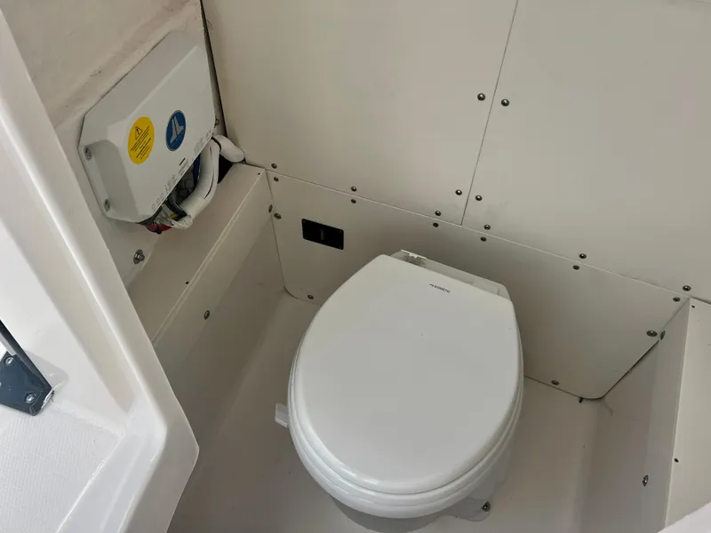 Slide: The Image of 2025 Robalo 266 Cayman SD boat bathroom with Dometic toilet and electrical panel. - 30