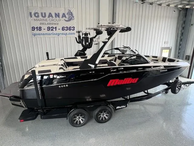 Slide: The Image of 2024 Malibu M220 black boat on trailer at Iguana Marine Group showroom. - 3