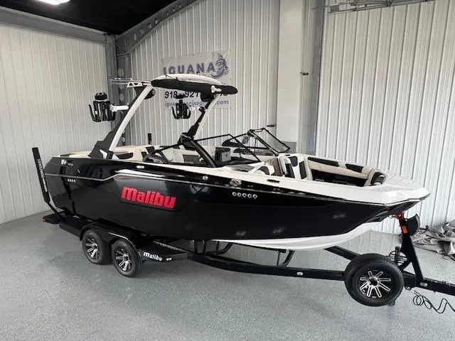 Slide: The Image of 2024 Malibu M220 boat in showroom, black and white exterior, on trailer. - 4