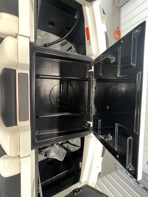 Slide: The Image of 2024 Malibu M220 boat storage compartments open, showcasing spacious interior. - 9