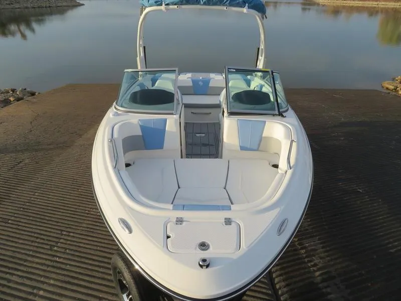 Slide: The Image of 2024 Chaparral 21 Surf boat with open bow seating, docked by a calm lake. - 4