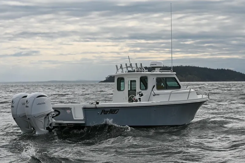 Slide: The Image of 2025 Parker 2420 Sport Cabin boat navigating choppy waters under cloudy skies. - 1