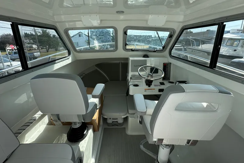 Slide: The Image of Interior of a 2025 Parker 2420 Sport Cabin boat with modern seating and steering console. - 12