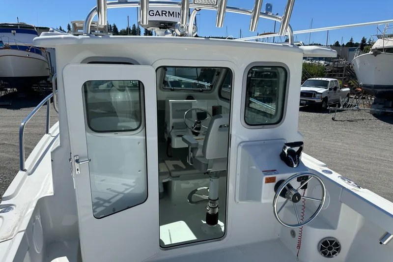 Slide: The Image of 2025 Parker 2420 Sport Cabin boat with open cabin door and visible steering wheel. - 15