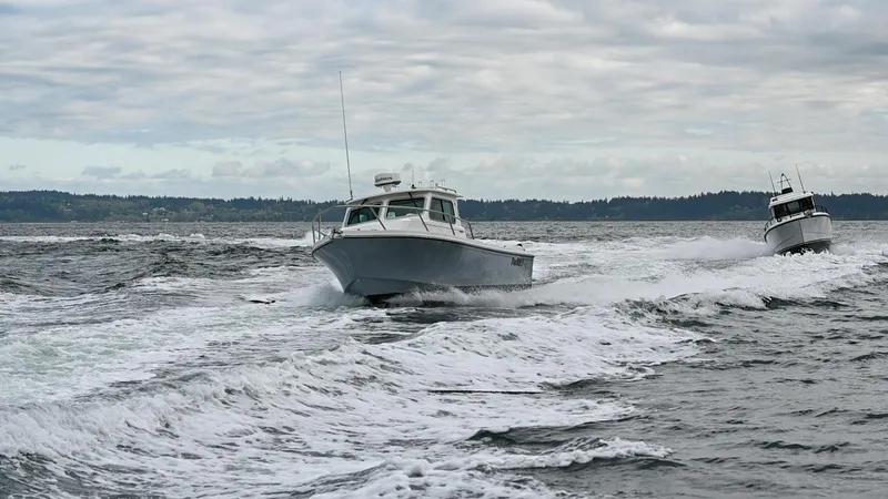 Slide: The Image of 2025 Parker 2420 Sport Cabin navigating choppy waters under cloudy skies. - 2