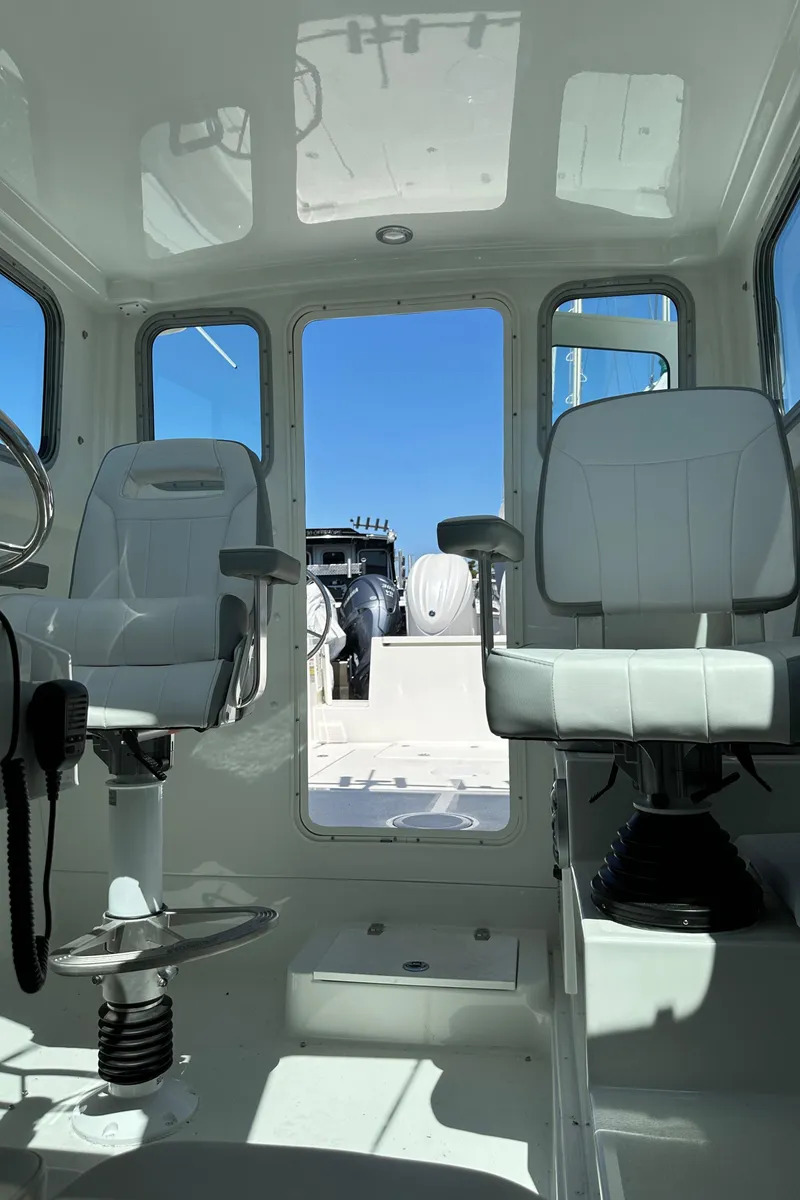 Slide: The Image of Interior of 2025 Parker 2420 Sport Cabin boat with white seating and steering wheel. - 21