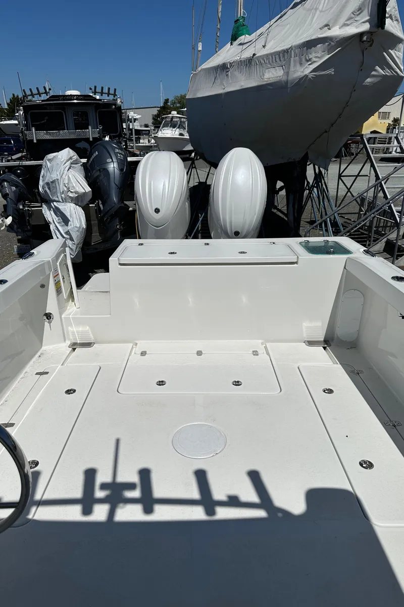 Slide: The Image of 2025 Parker 2420 Sport Cabin boat with dual outboard motors in a marina setting. - 22