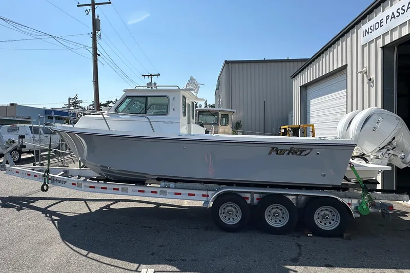 Slide: The Image of 2025 Parker 2420 Sport Cabin boat on a trailer outside a warehouse. - 7