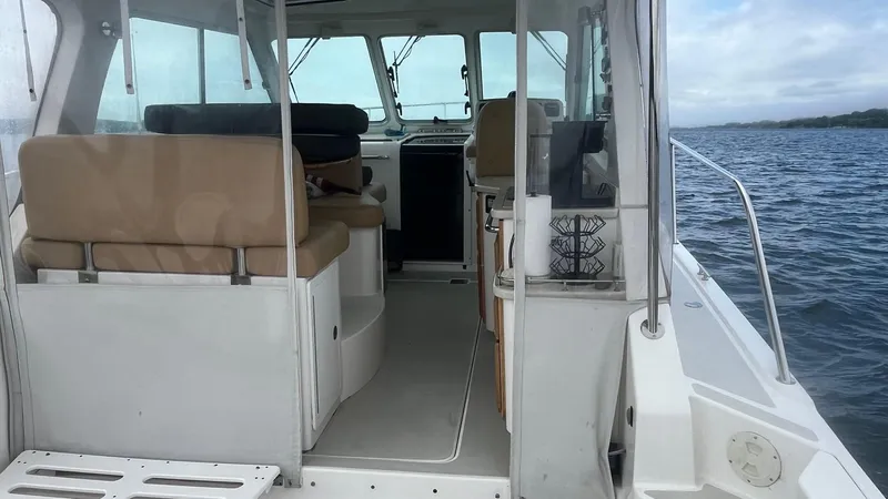 Slide: The Image of 2014 Back Cove 34 boat interior with beige seating, on calm water. - 10