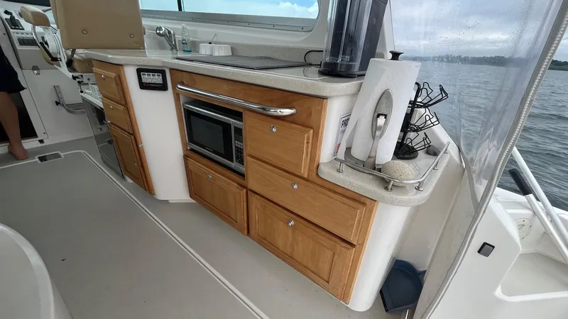 Slide: The Image of 2014 Back Cove 34 boat interior with kitchenette, featuring wooden cabinets and a microwave. - 11
