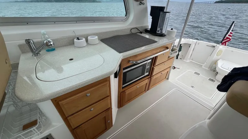 Slide: The Image of 2014 Back Cove 34 yacht interior kitchen with sink, microwave, and wooden cabinets. - 13