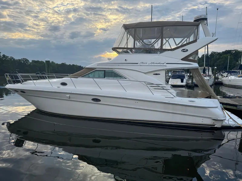 Slide: The Image of 2003 Sea Ray 400 Sedan Bridge yacht docked at marina, under cloudy sky. - 2