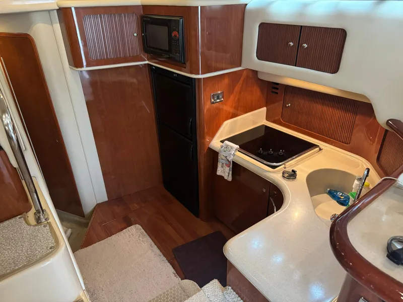 Slide: The Image of 2003 Sea Ray 400 Sedan Bridge yacht kitchen with wood cabinetry and modern appliances. - 21
