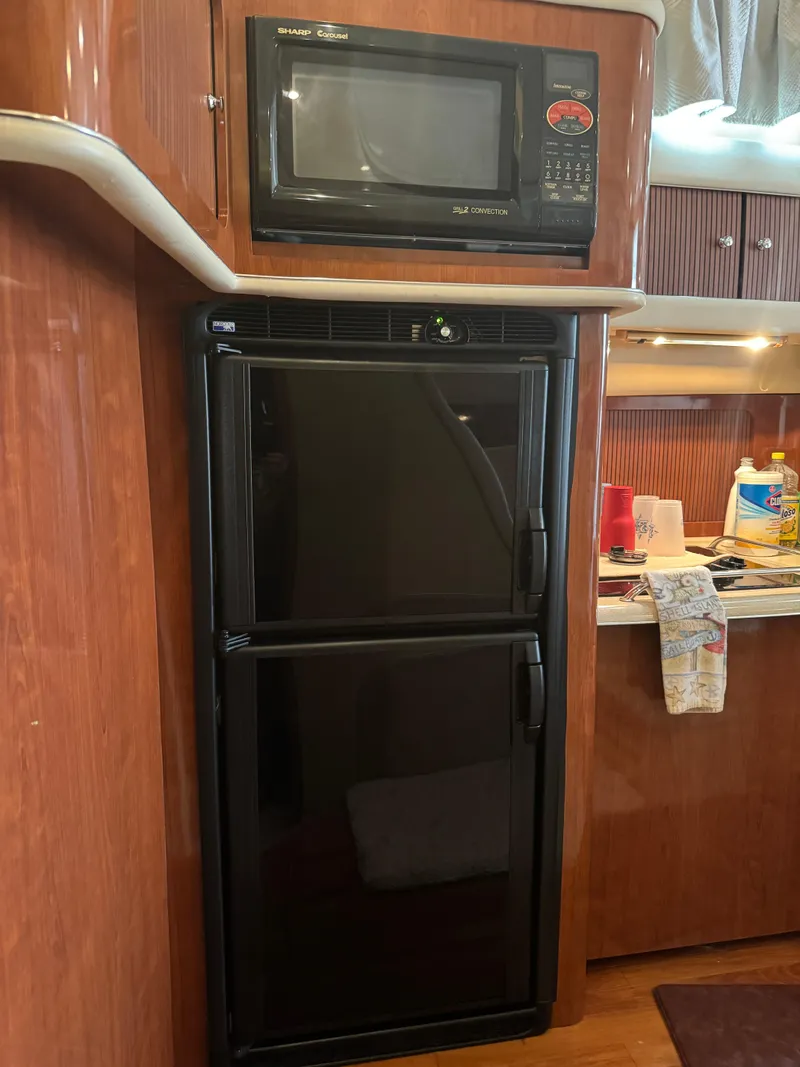 Slide: The Image of 2003 Sea Ray 400 Sedan Bridge kitchen with microwave and fridge. - 22