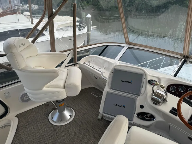 Slide: The Image of 2003 Sea Ray 400 Sedan Bridge helm with Garmin navigation, luxurious seating, and waterfront view. - 7
