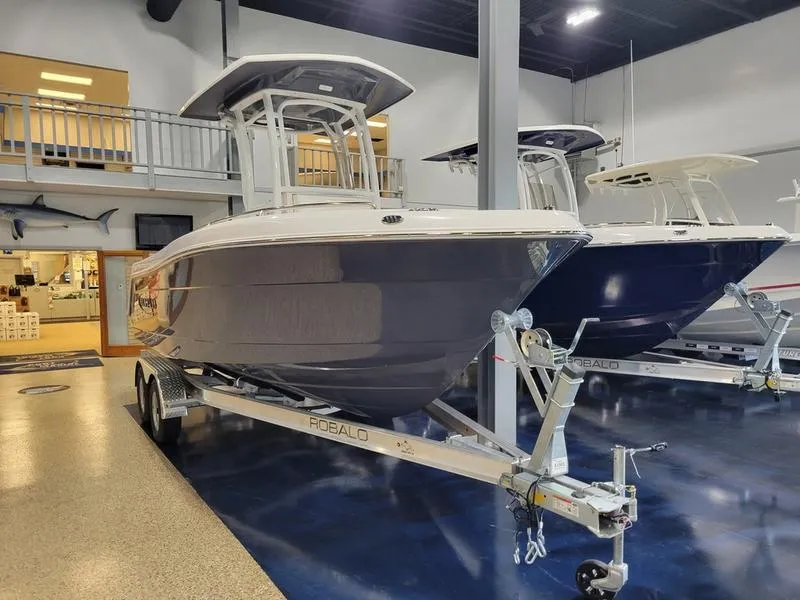 Slide: The Image of 2025 Robalo 222 CC boat on trailer in showroom. - 2