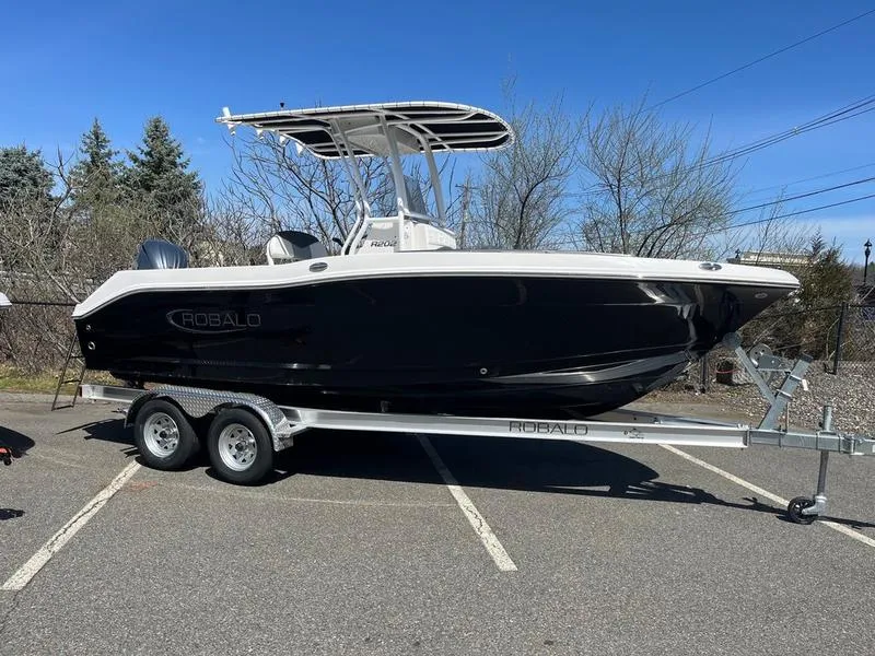 The Image of 2025 Robalo R 202 EX boat on trailer, parked outdoors, clear sky background. - 0