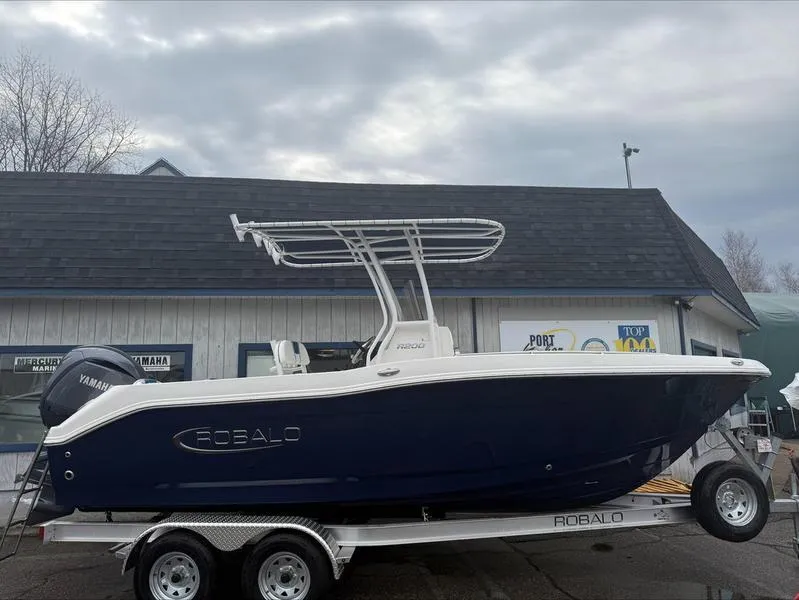 Slide: The Image of 2025 Robalo R 200 boat on trailer, parked outside a building under cloudy skies. - 3