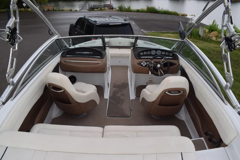 Slide: The Image of 2013 Cobalt 210 WSS boat interior with brown and white seating, dashboard, and steering wheel. - 2