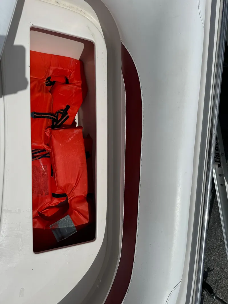 Slide: The Image of Storage compartment with red life jackets on a 1999 Hurricane 232 FUN DECK boat. - 22