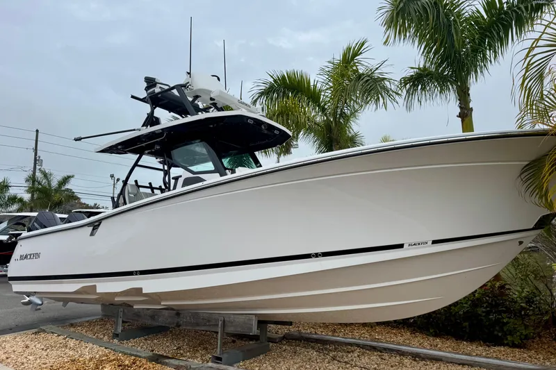 Slide: The Image of 2025 Blackfin 332 CC boat displayed outdoors with palm trees in the background. - 61