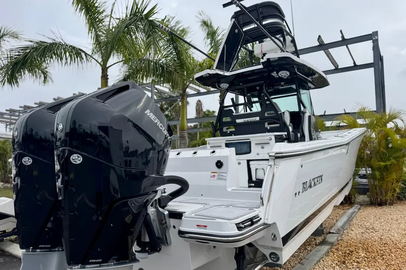 Slide: The Image of 2025 Blackfin 332 CC boat with dual Mercury engines, parked near palm trees. - 63