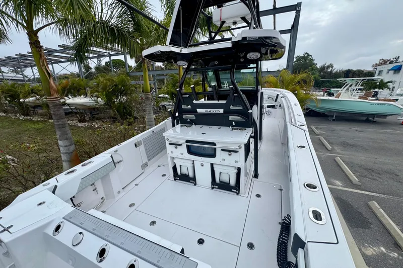 Slide: The Image of 2025 Blackfin 332 CC boat with spacious deck and modern design, parked near palm trees. - 70