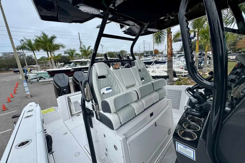 Slide: The Image of 2025 Blackfin 332 CC boat interior with seating and control panel, docked near palm trees. - 87
