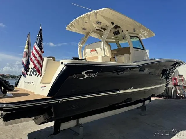 Slide: The Image of 2022 Scout 330 LXF boat with flags, docked under clear blue sky. - 11