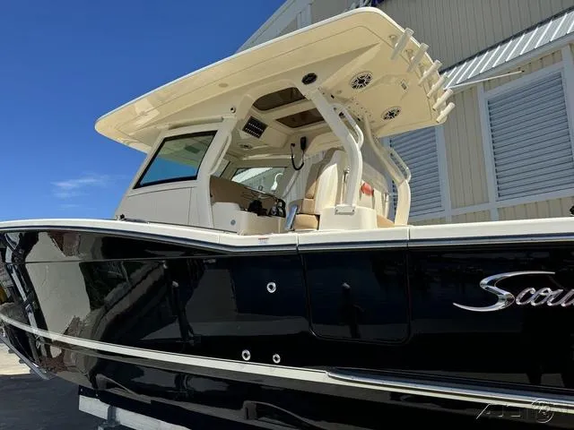 Slide: The Image of 2022 Scout 330 LXF boat with black hull and beige interior, docked near a building. - 22