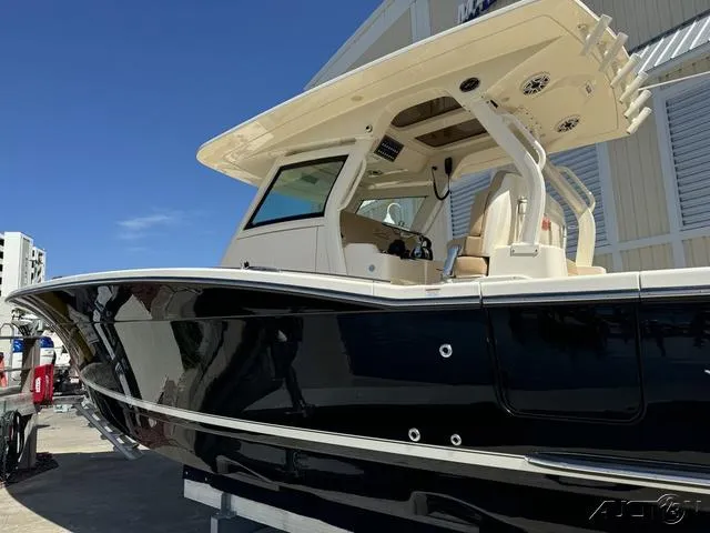 Slide: The Image of 2022 Scout 330 LXF boat with sleek black hull and beige interior, docked under clear blue sky. - 23